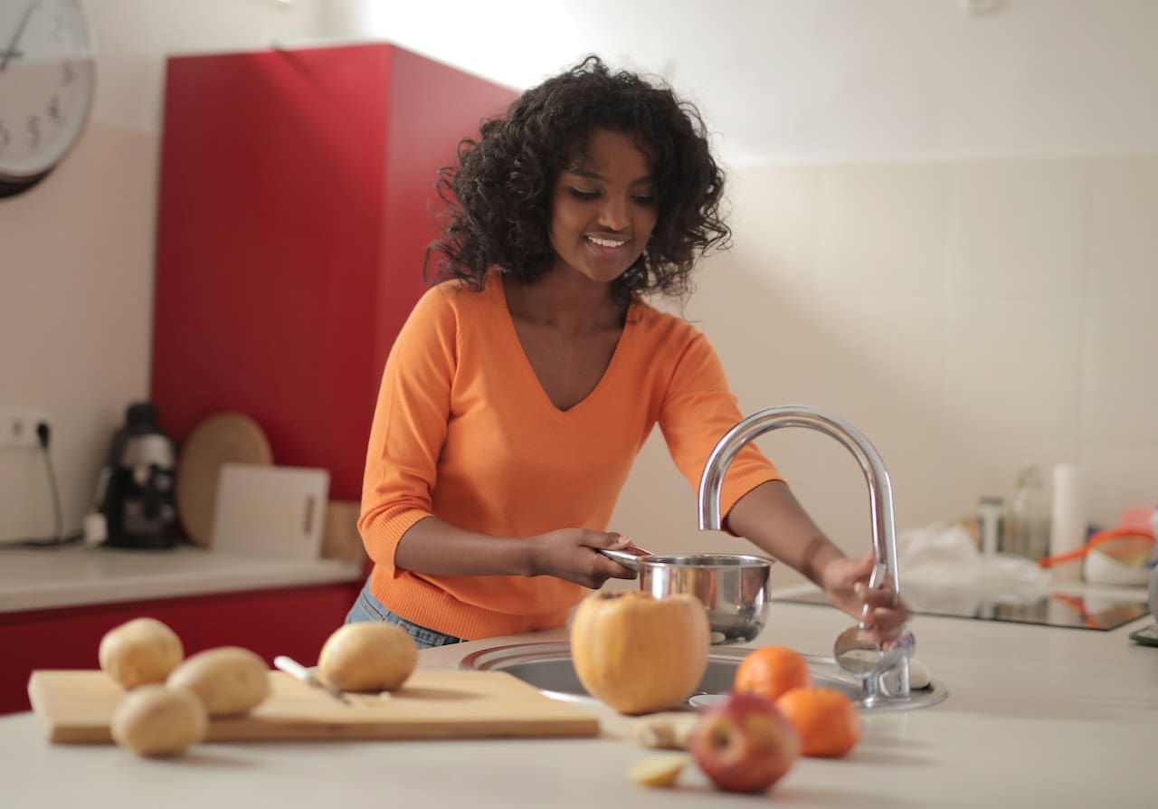 An image of a homeowner pouring cloudy tap water into a pot for cooking, emphasizing the importance of filtered water in Irving kitchens.
