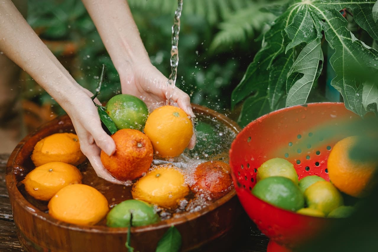 A picture of a person rinsing fruits and vegetables under tap water that appears cloudy, underscoring concerns about the suitability of unfiltered water for cooking in Grand Prairie homes.