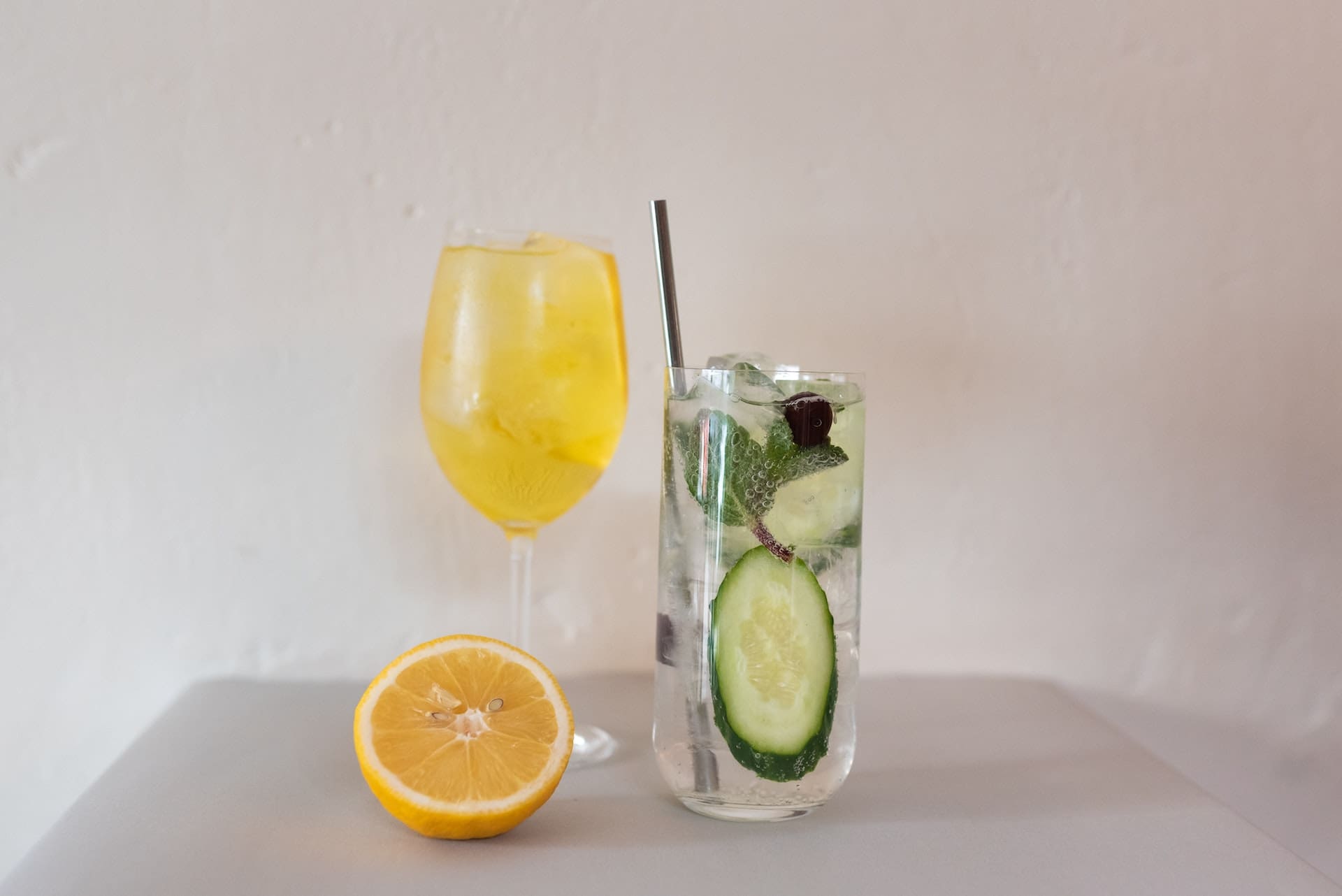 A cozy porch setting with wicker furniture. A couple enjoys the evening, sipping from glasses filled with sparkling water, ice cubes, and cucumber slices.