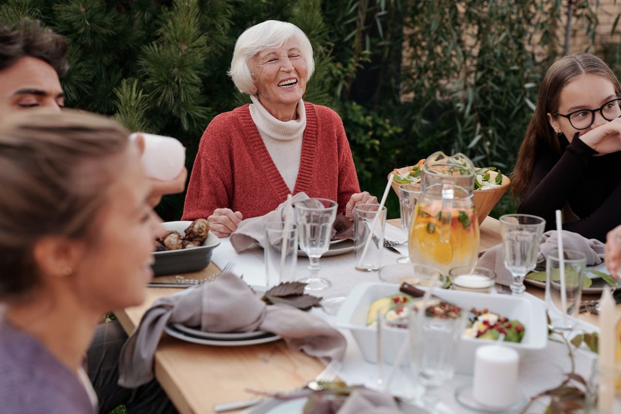 A rooftop terrace of a high-rise condo, overlooking the city and waterway. Residents enjoy a dinner party, with a sleek water dispenser offering chilled, filtered water to guests.