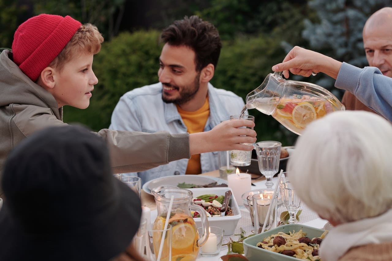 A heartwarming scene of a family enjoying a picnic in their backyard, under the shade of towering trees, sipping on refreshing beverages made with pure water, showcasing the joy of outdoor leisure in Sugar Land.