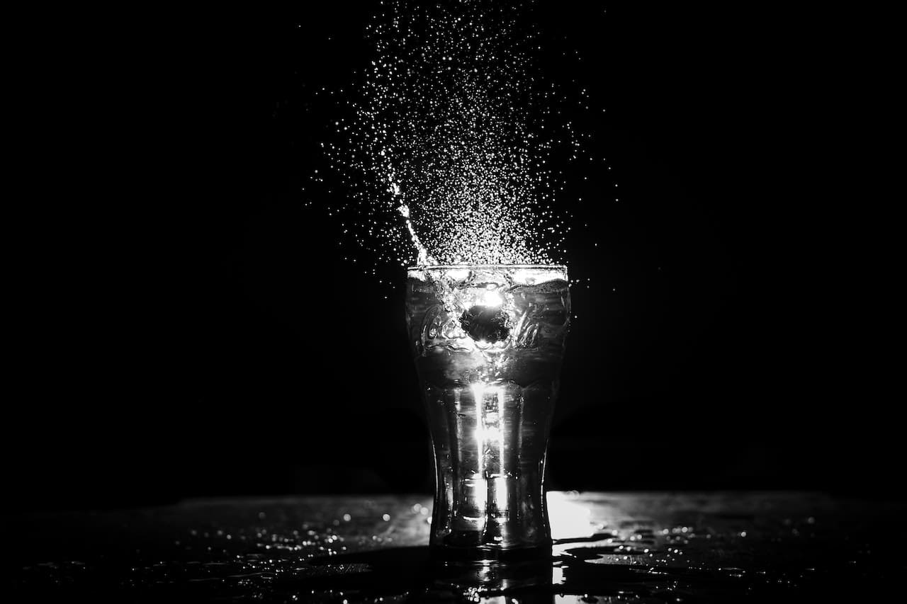A close-up of a glass filled with water on a counter. Floating on the surface are tiny particles, giving the water a cloudy appearance.