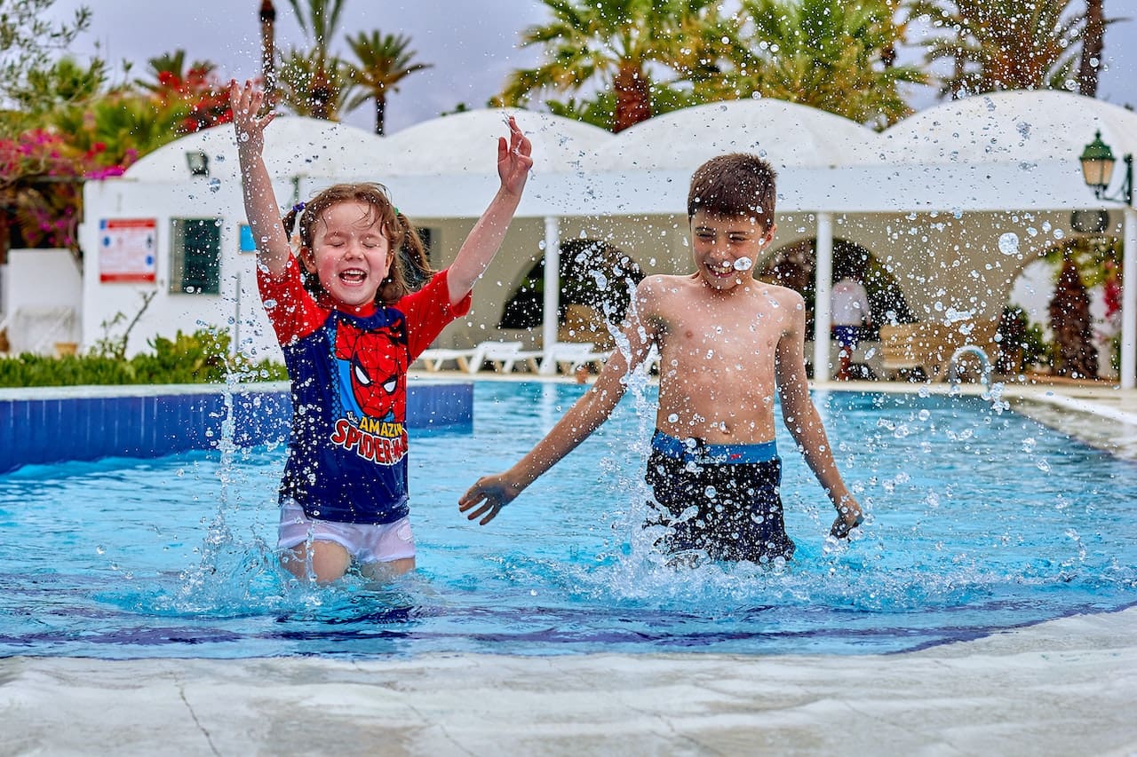 A heartwarming scene of a family enjoying a day by their swimming pool, with children splashing in the water and parents relaxing by the poolside, illustrating the joys of outdoor living in Killeen.