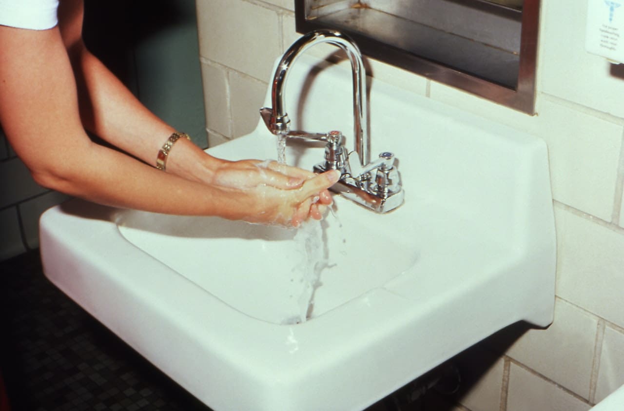 An image of a resident in Mission expressing frustration while cleaning mineral deposits from faucets and showerheads, underscoring the challenges of hard water in the area.