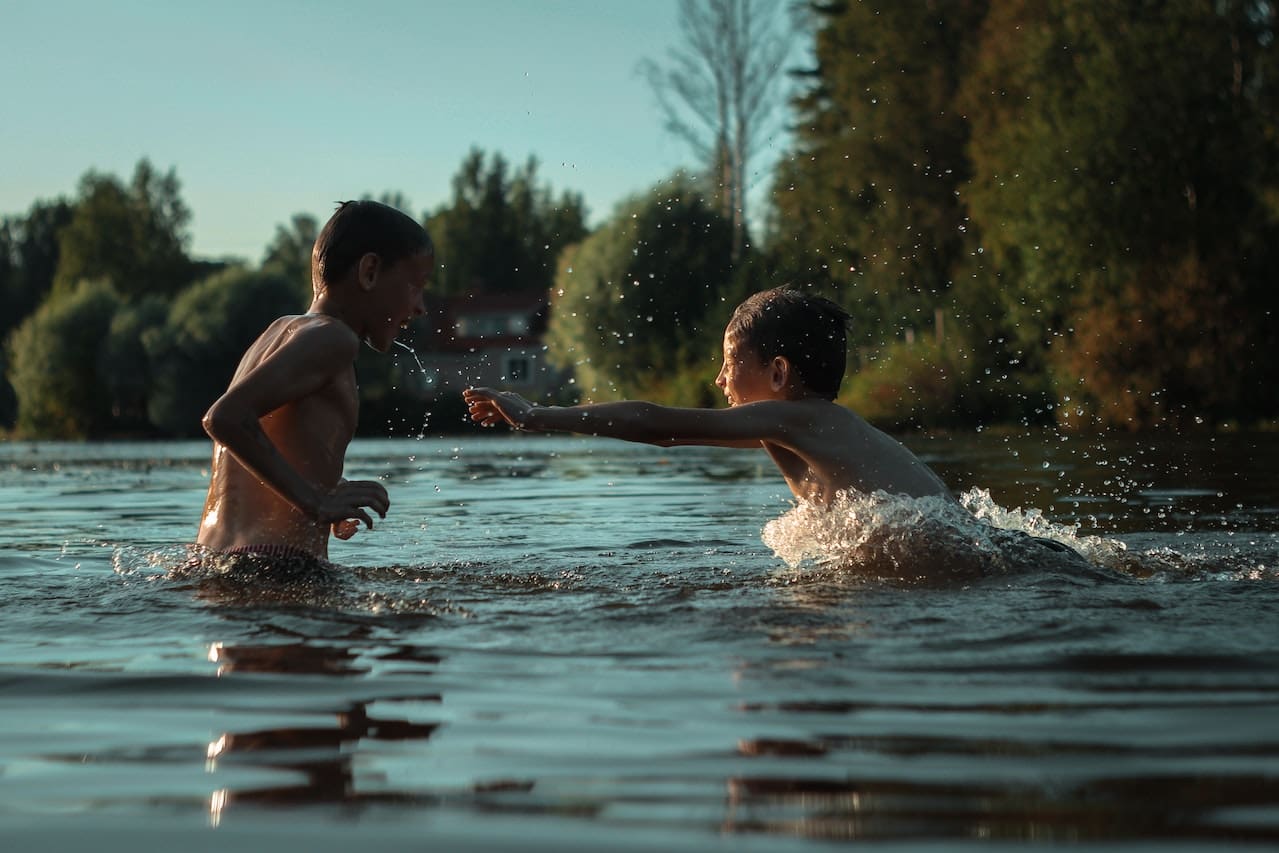 A backyard scene with children playing in an inflatable pool, laughing and splashing. Nearby, a garden blooms, and a sprinkler system ensures the lawn stays green, all benefiting from filtered water.