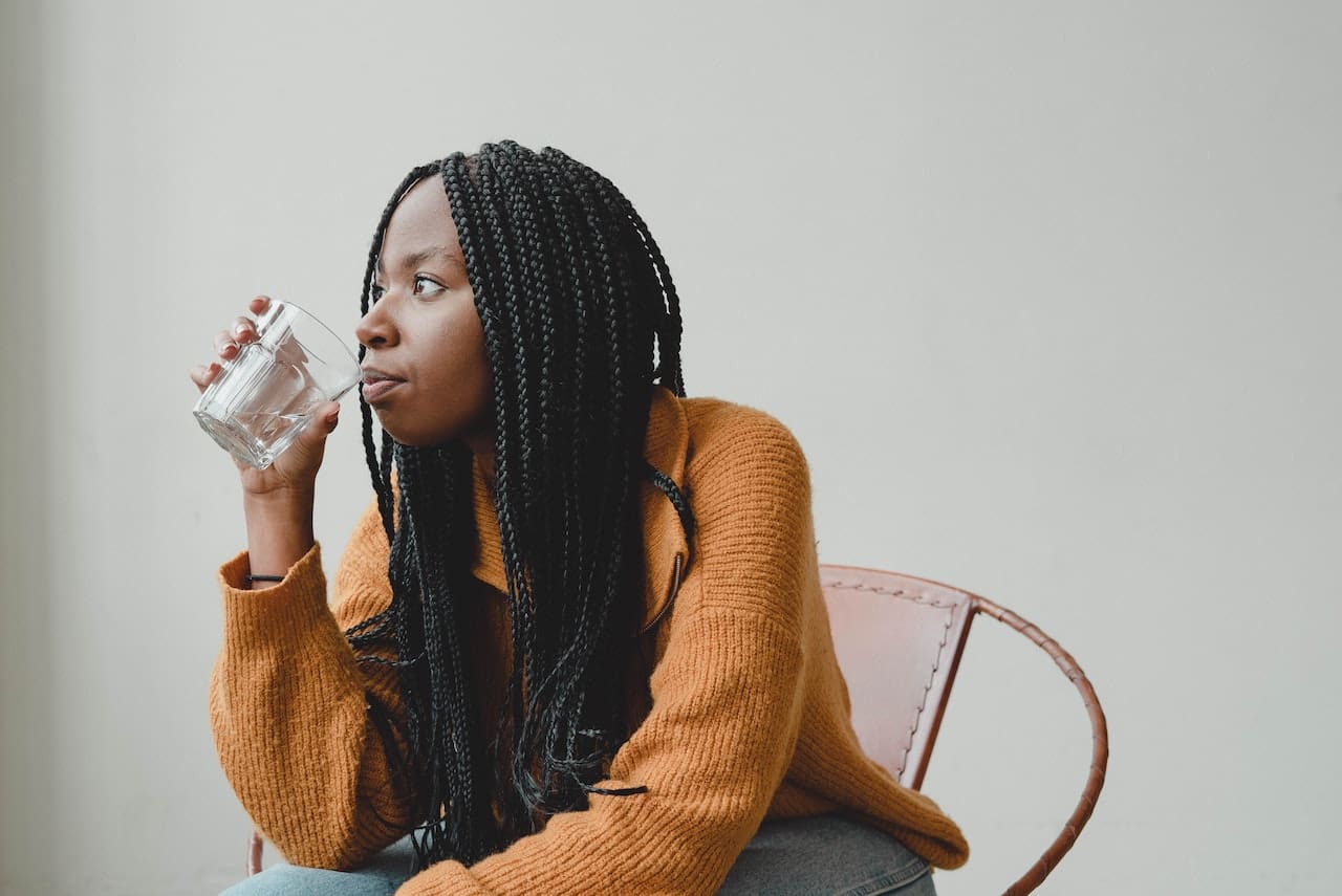 An image of an elderly lady in Edinburg encountering a cloudy glass of tap water while trying to stay hydrated, highlighting the importance of filtered water for drinking.