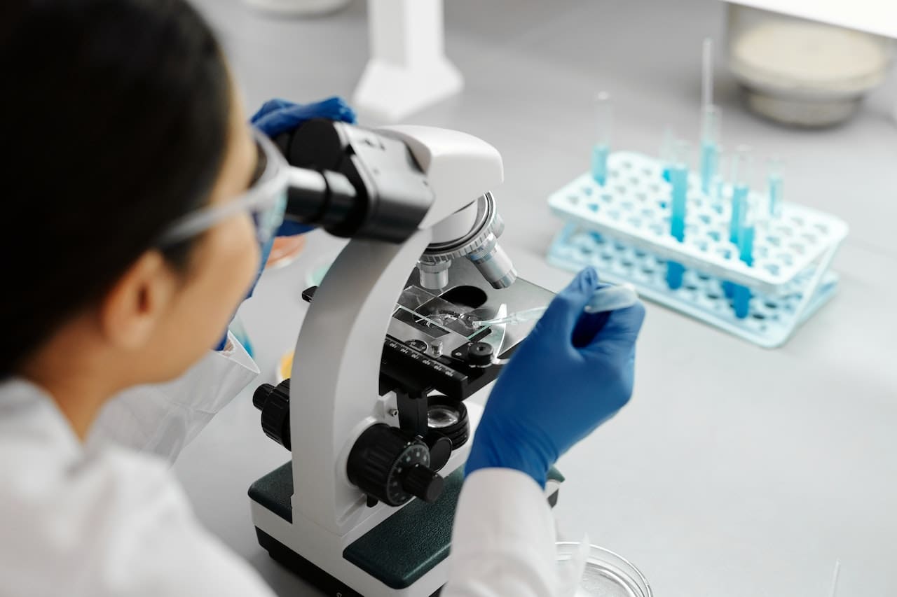 A scientist in a lab coat examining a water sample from a local lake under a microscope, with a concerned expression.