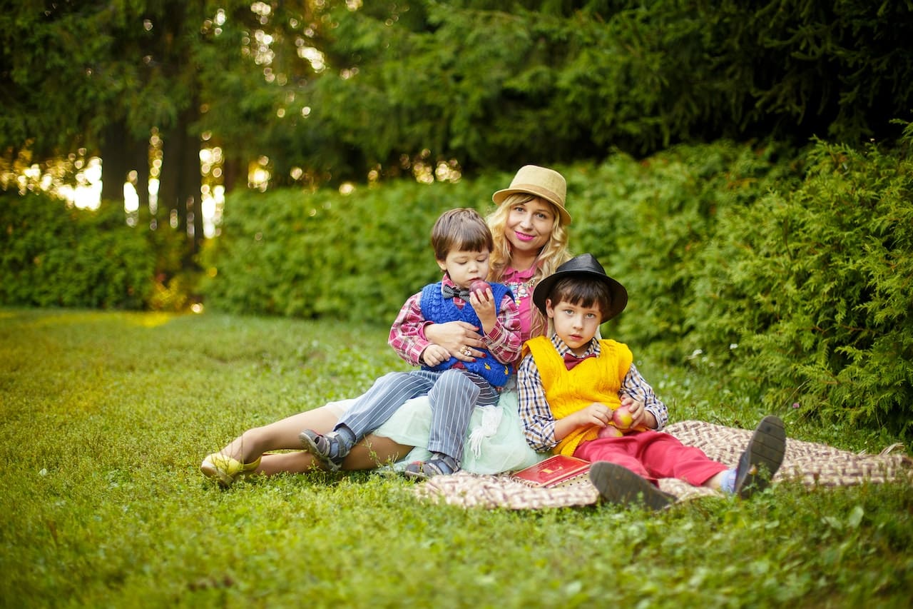 A heartwarming scene of a family picnicking in their backyard, under the shade of towering trees, sipping on refreshing beverages made with pure water, showcasing the joy of outdoor leisure in Grand Prairie.