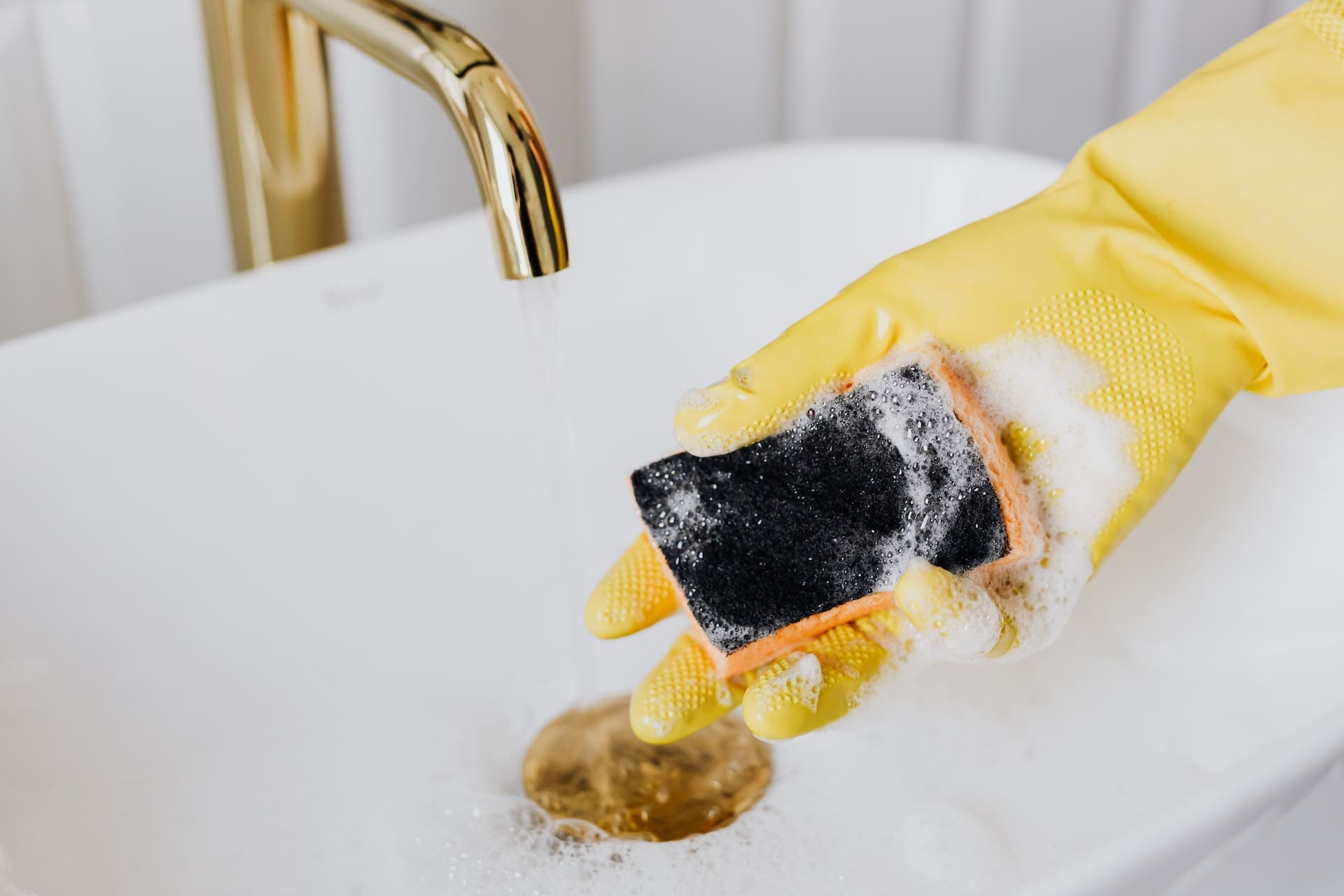 A bathroom scene with a filled sink. The water appears stagnant, with a thin oily film on the surface, and a few stray feathers floating, suggesting contamination.