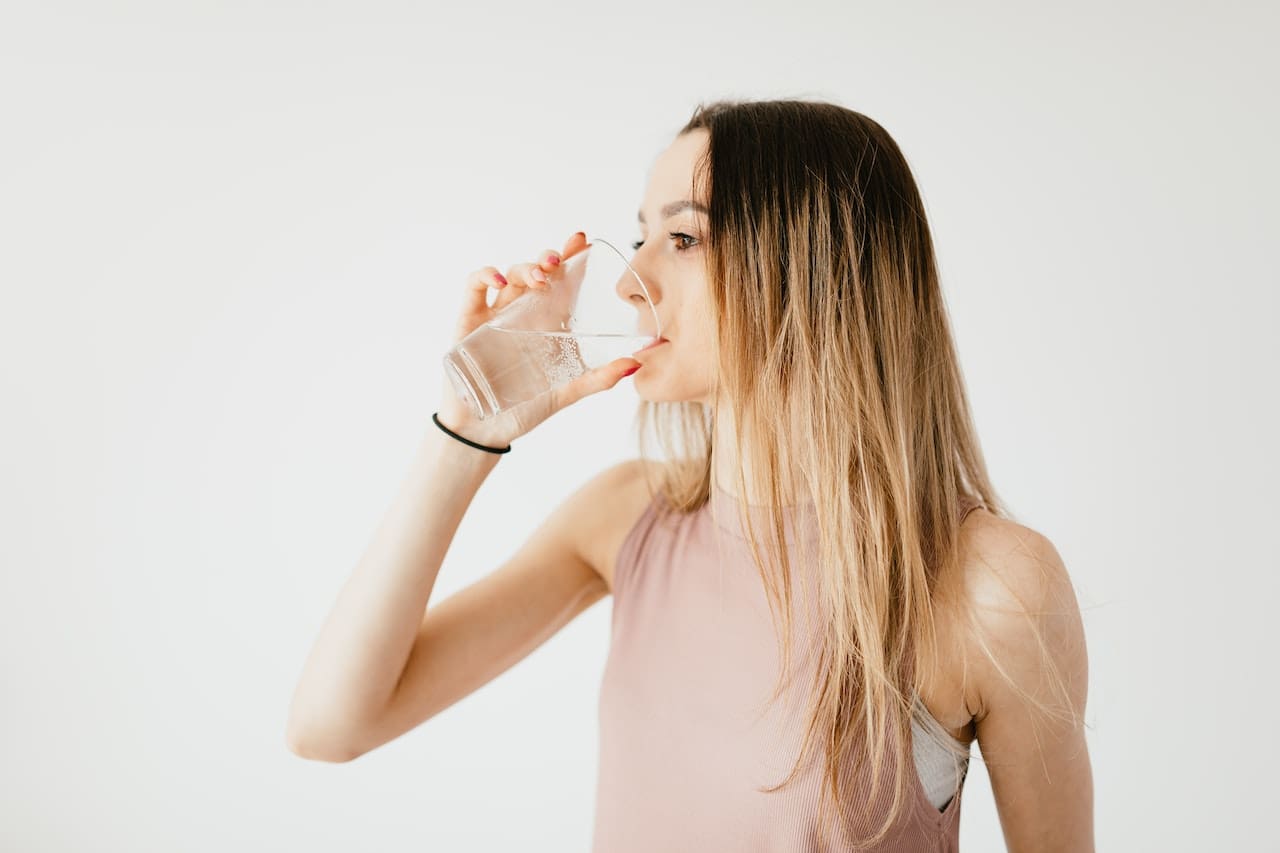 An image of a resident in New Braunfels frustrated with the taste of tap water while trying to enjoy a refreshing glass, outdoors, highlighting concerns about water quality for drinking.