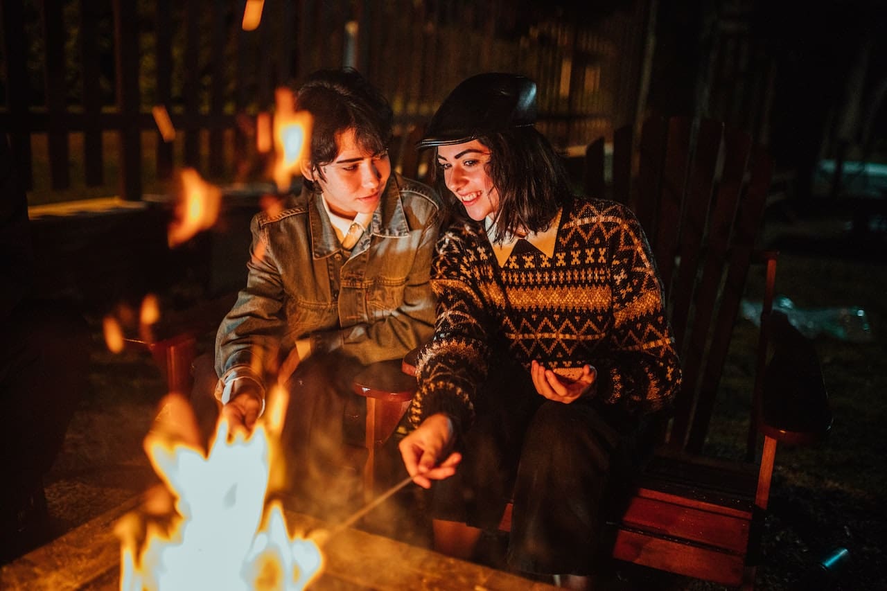 A heartwarming scene of friends gathered around a fire pit in their backyard, enjoying roasted marshmallows and warm beverages made with pure water, exemplifying the pleasures of outdoor leisure in Round Rock.