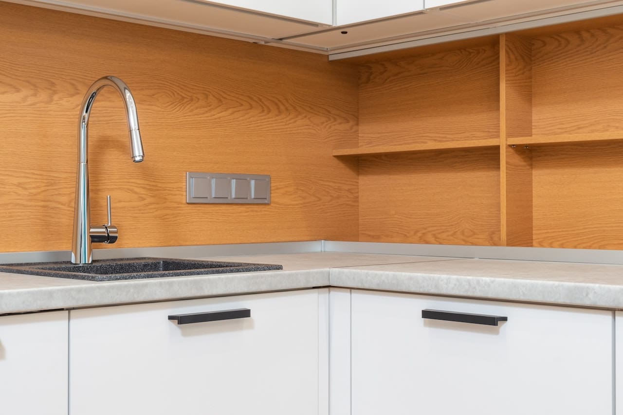 A modern kitchen with stainless steel appliances. A family gathers around, filling up glasses from a filtered water tap, with the water sparkling and inviting.