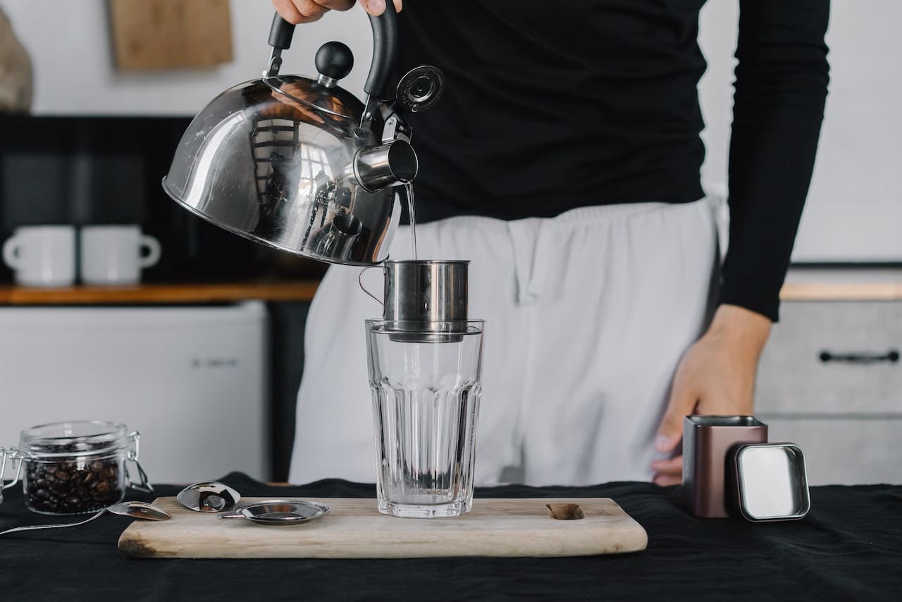A Teenager Makes A Smoothie, Pouring Clear Water From A Filtered Tap Into A Blender Filled With Fresh Fruits