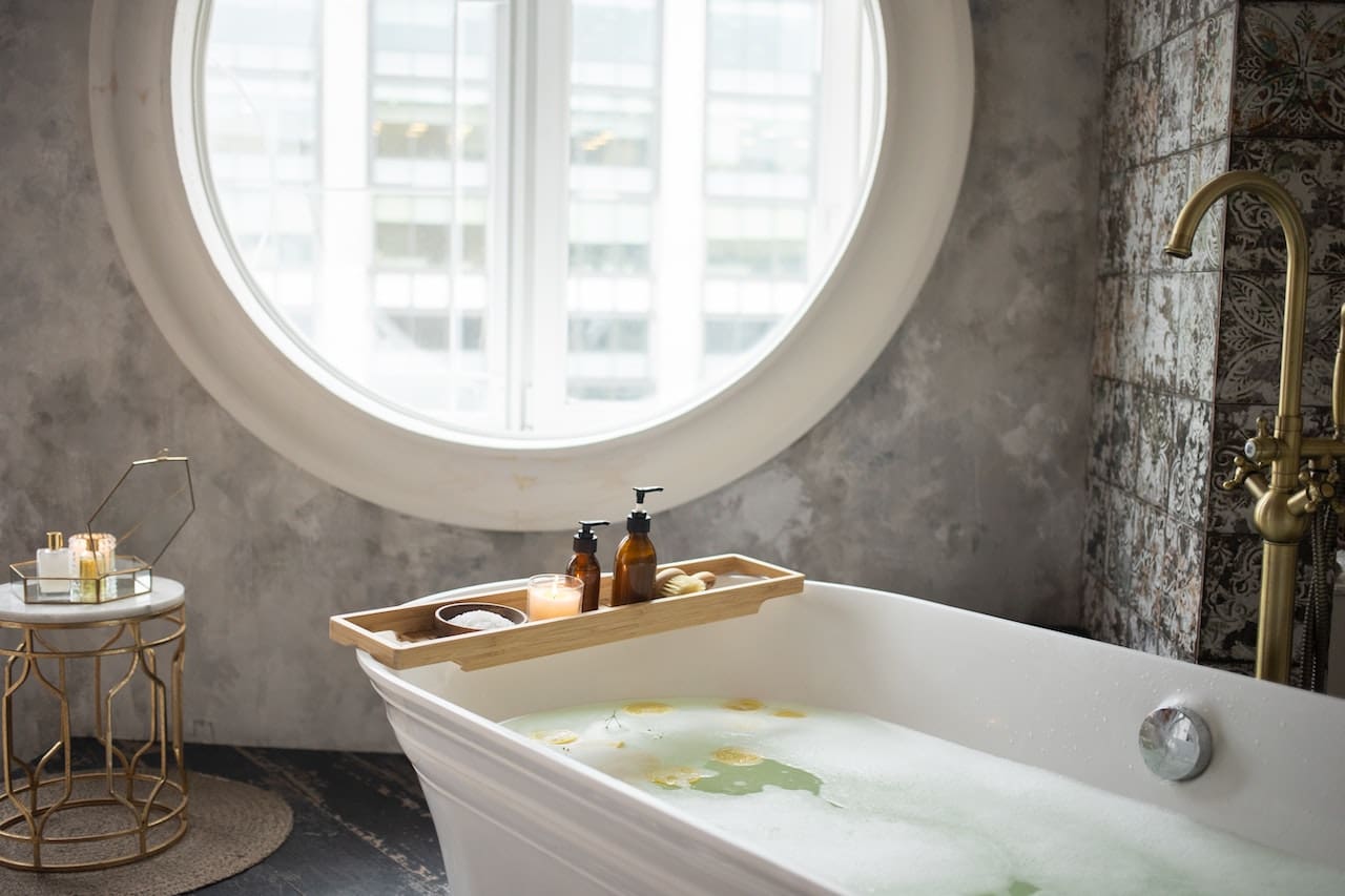 A picture near a bathtub of a homeowner frustrated with soap scum and mineral buildup on bathroom tiles and fixtures, illustrating the impact of hard water in Beaumont homes.