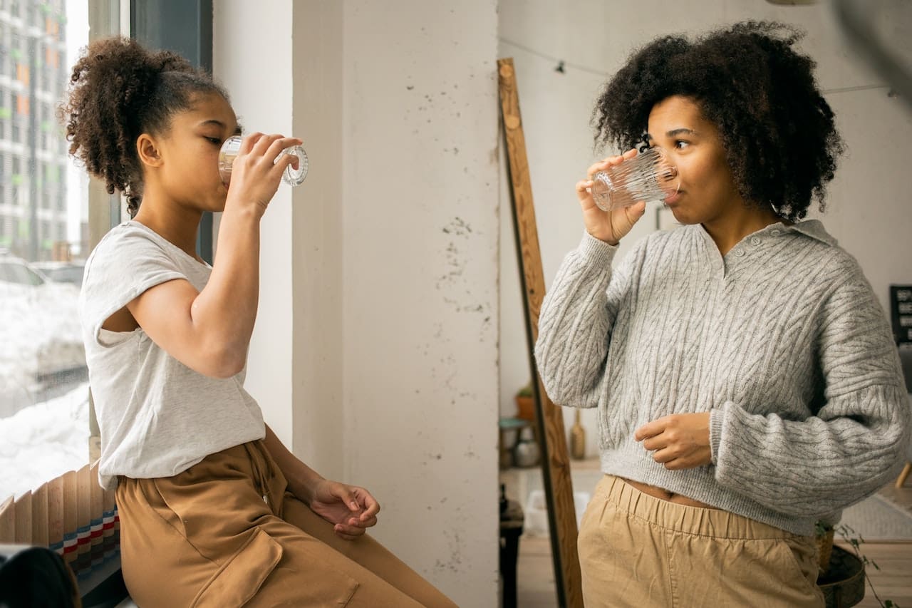 An image of a teenage girl in Midland frustrated with the taste of tap water while trying to enjoy a refreshing glass in the back yard, highlighting concerns about water quality for drinking.