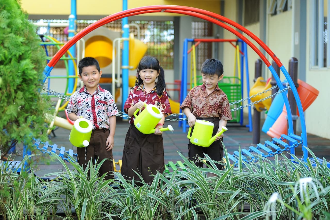 A photo-realistic image of a vibrant backyard garden, where children help water the plants using a watering can, connecting with Austin's eco-friendly ethos.