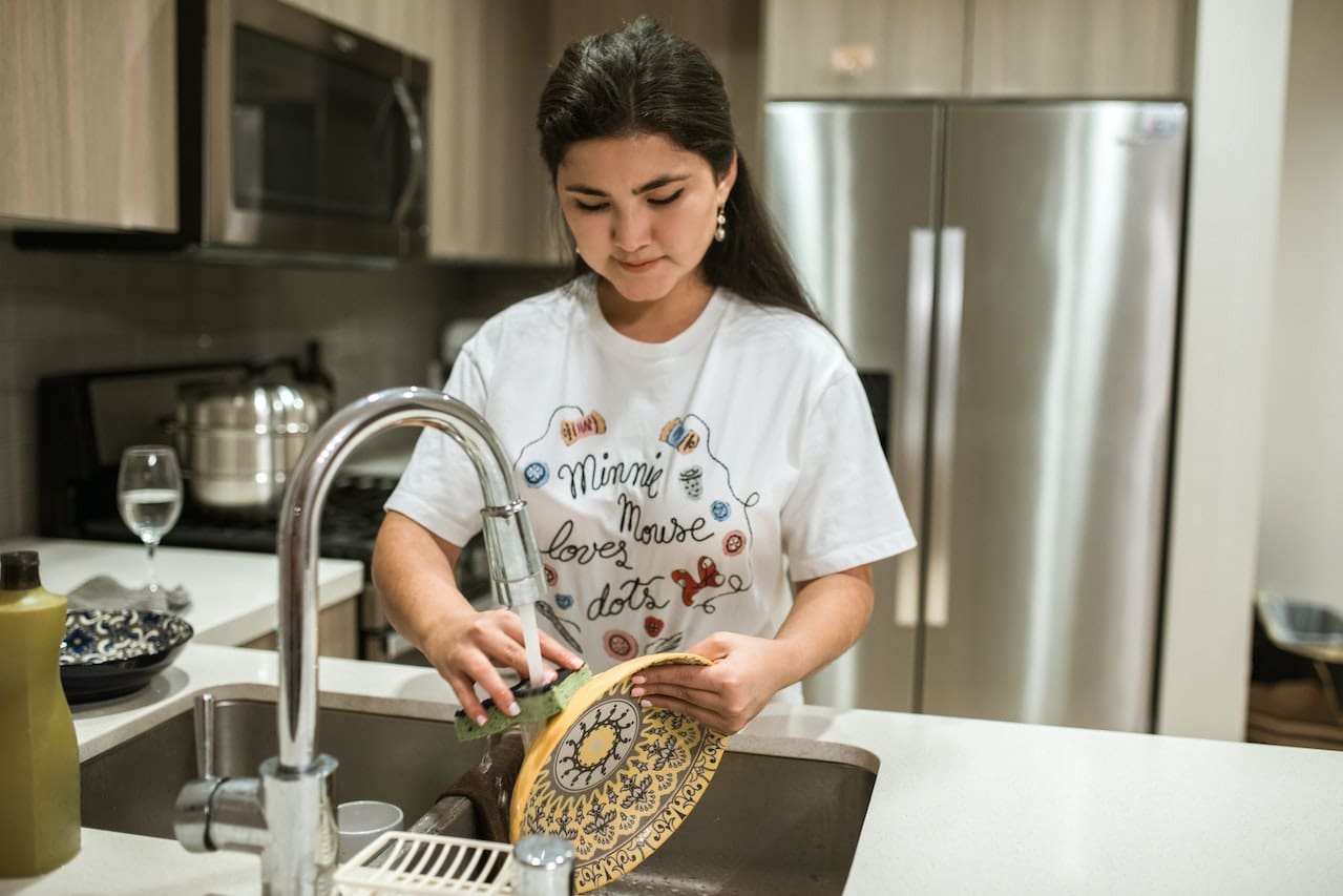 A closeup of a person examining white spots on dishes caused by hard water stains, underlining the challenges of water quality in Abilene.
