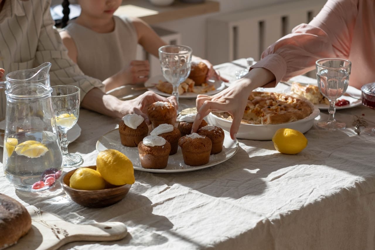 A sunlit patio of a beachfront home. A family enjoys breakfast, with a pitcher of clear water adorned with citrus slices at the center of the table, emphasizing the importance of clean water even in coastal settings.