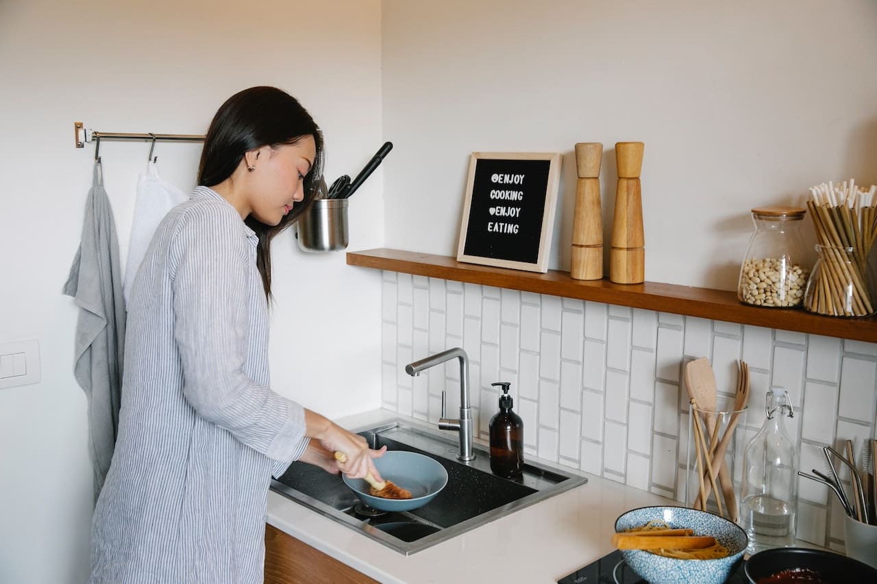 An image of a homeowner scrubbing away hard water stains from a plate caused by unfiltered water, illustrating the impact of water quality on daily life in College Station households.