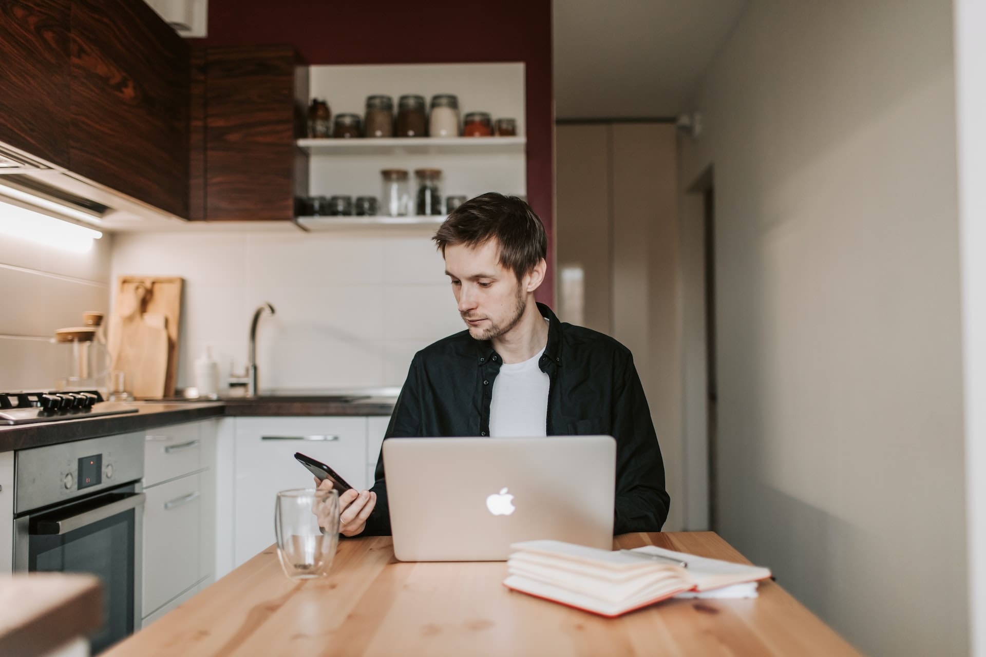 A kitchen scene with a glass of water placed next to an open laptop